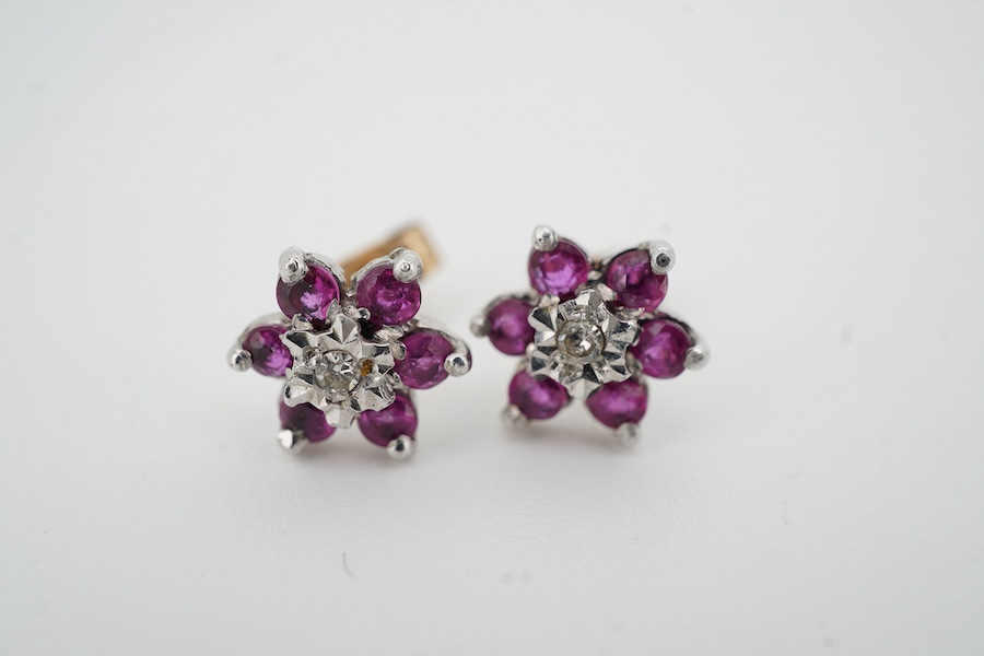 A pair of ruby and diamond stud earrings, of cluster design, set with a circular-cut rubies and single-cut diamonds, mounted in 9ct white gold, 8.5mm diameter each, post fittings, British hallmarks